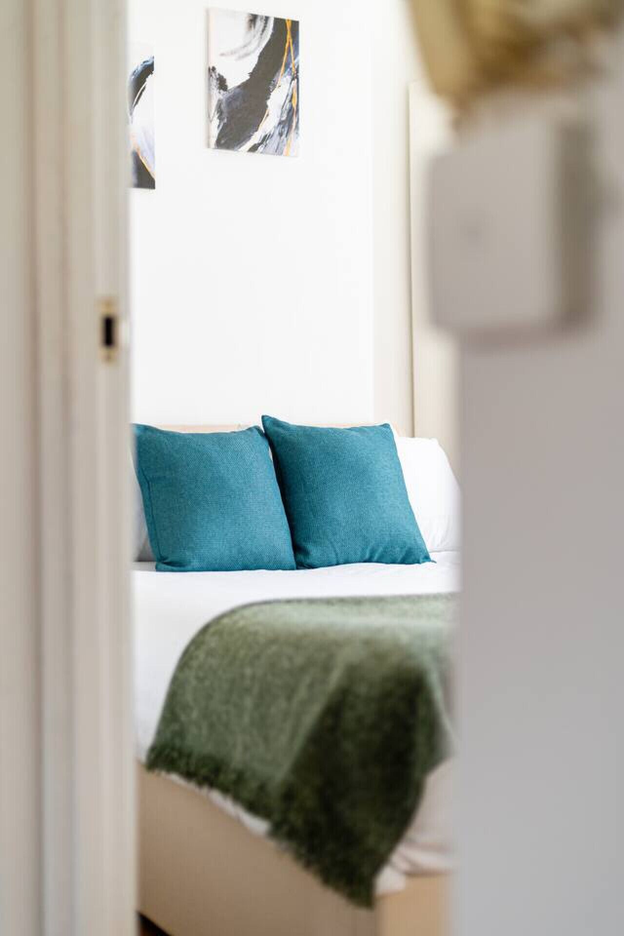 Une chambre à coucher avec un lit, des oreillers turquoise et une couverture verte.