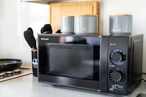 A kitchen with a microwave, a coffee maker, and a sugar container. - West Hampstead Hub - 1 bedroom spacious apartment (Greater London)