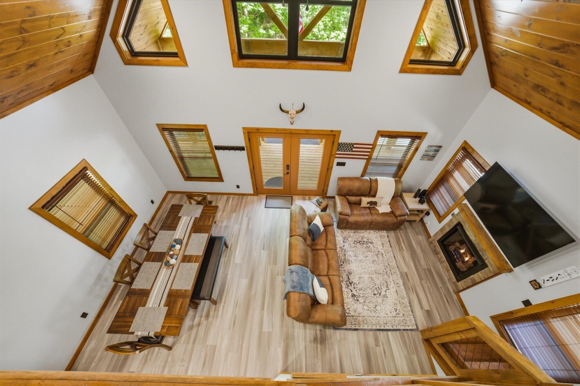 Un'ampia zona giorno in stile loft con soffitto alto, travi in legno, camino e un grande televisore.