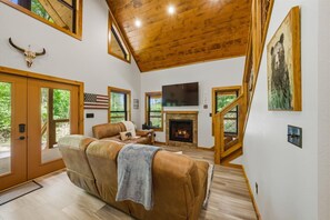 Ein geräumiges Wohnzimmer mit Kamin, Ledersofa und großem Fernseher.