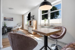 Ein modernes Wohnzimmer mit einer Couch, einem Couchtisch und einem Essbereich mit Tisch und Stühlen.