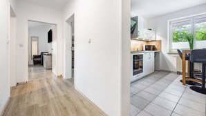 Una cocina moderna con armarios blancos, encimera de madera y ventana con vistas a zonas verdes.