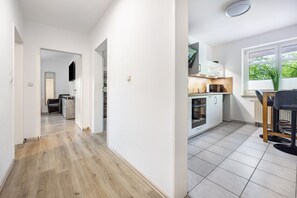 Una cocina moderna con armarios blancos, encimera de madera y ventana con vistas a zonas verdes.