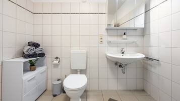Une salle de bain moderne équipée de toilettes, d’un lavabo et d’un meuble de rangement.