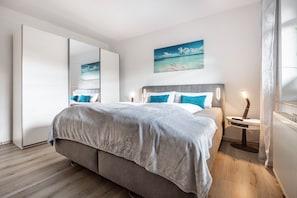 Un dormitorio moderno con cama, mesita de noche y una obra de arte colgada en la pared.