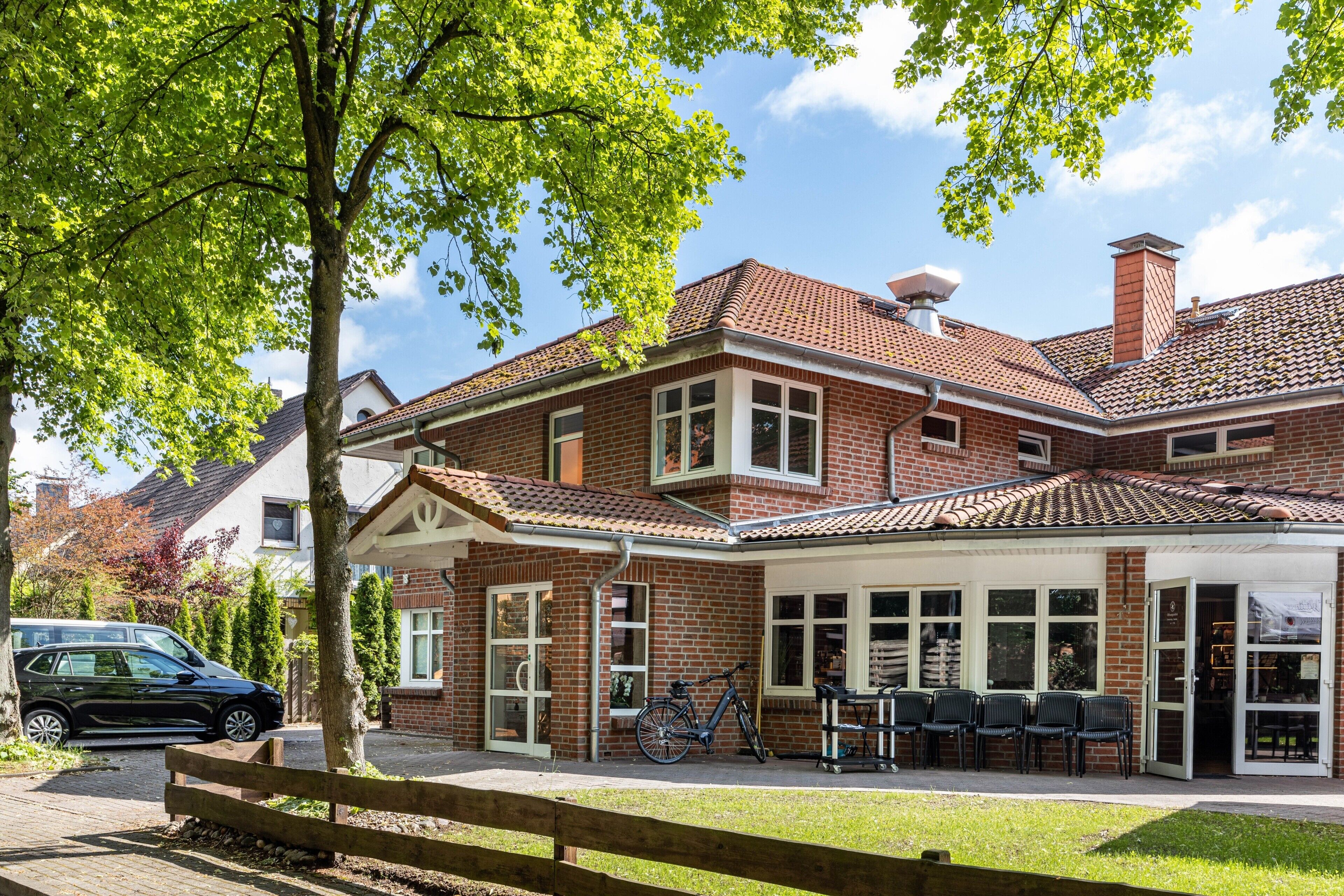 Ein Backsteinhaus mit Ziegeldach, einer überdachten Terrasse mit Sitzgelegenheiten und einem Fahrrad vor der Tür.