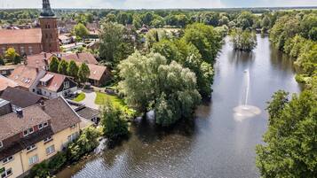 Een rivier die door een stad stroomt, met gebouwen aan één kant en een grote boom aan de andere kant.