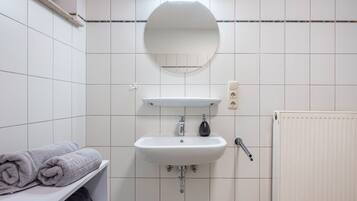 Ein Badezimmer mit Waschbecken, Spiegel, Handtuchhalter und Heizkörper.