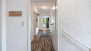 Um corredor com piso de madeira, uma placa com a inscrição 'Apartment Seaside' e uma porta à direita.