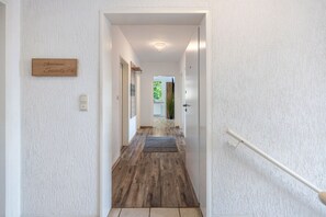 Ein Flur mit Holzboden, einem Schild mit der Aufschrift 'Apartment Seaside' und einer Tür rechts.
