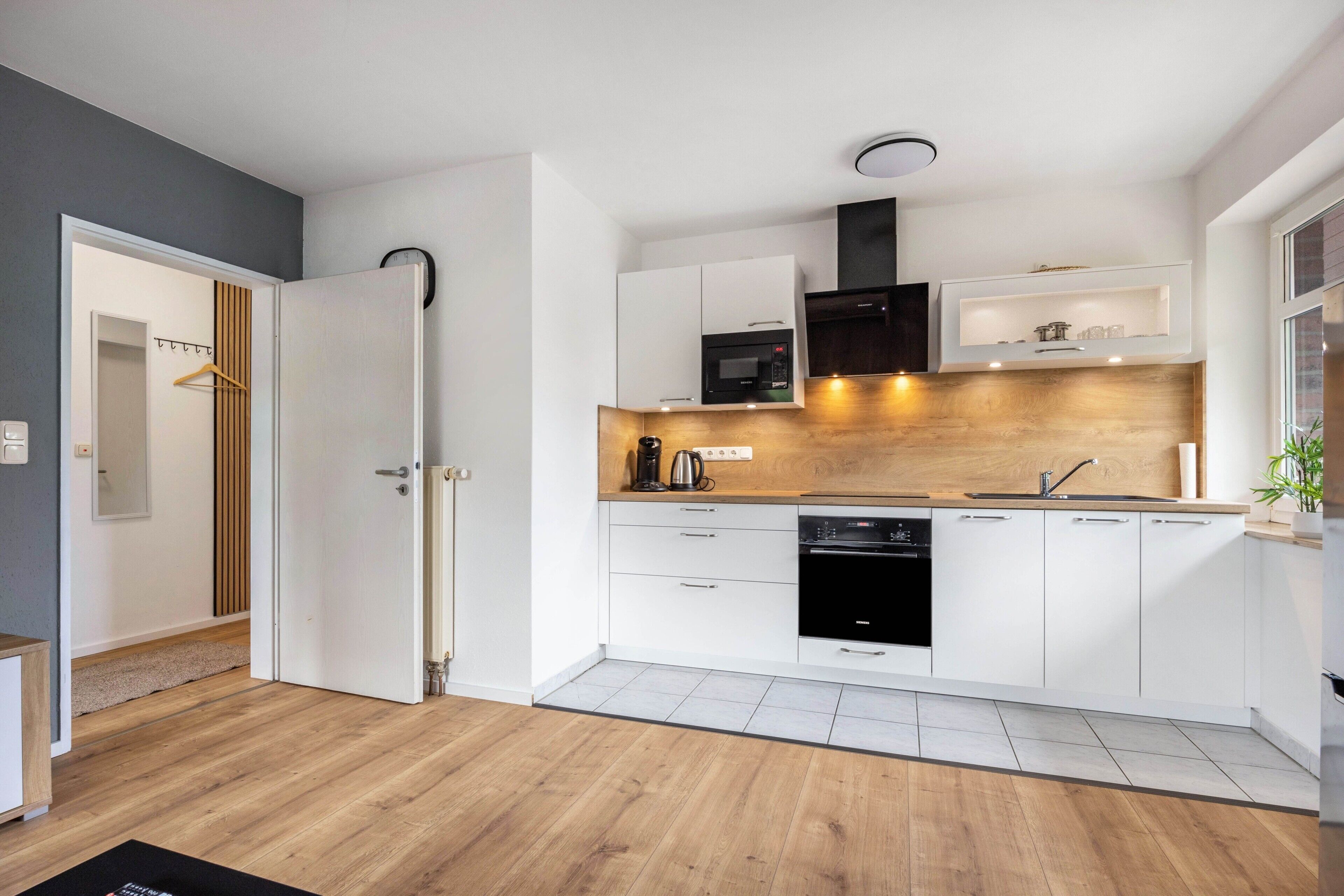 Una cucina moderna con mobili bianchi, forno a microonde, fornello e lavastoviglie.