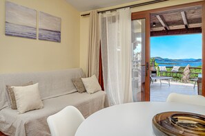 Una habitación con sofá, una mesa y vistas a un patio con mobiliario exterior.