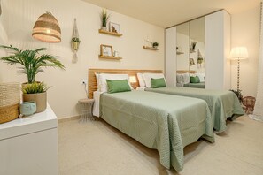 Un dormitorio con dos camas, un espejo grande, mesitas de noche y una planta en maceta.