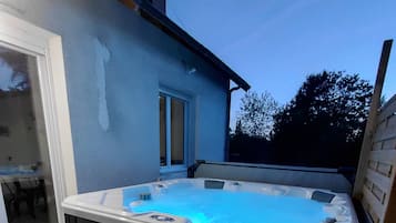 Un bain à remous doté d’une terrasse en bois et d’une porte vitrée donnant sur un espace extérieur.