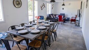 A dining area with a long table set for six, chairs, and a clock on the wall. - La Parenthèse de Sologne – Pool – Hot Tub – 25 min to Beauval (Gy-en-Sologne)