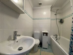 Et badeværelse med vask, toilet og bruser.