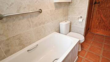 A bathroom with a bathtub, toilet, and a wooden door.