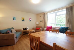 Ein gemütliches Wohnzimmer mit einem Holzesstisch, zwei Sofas und einem fenster mit Vorhängen.