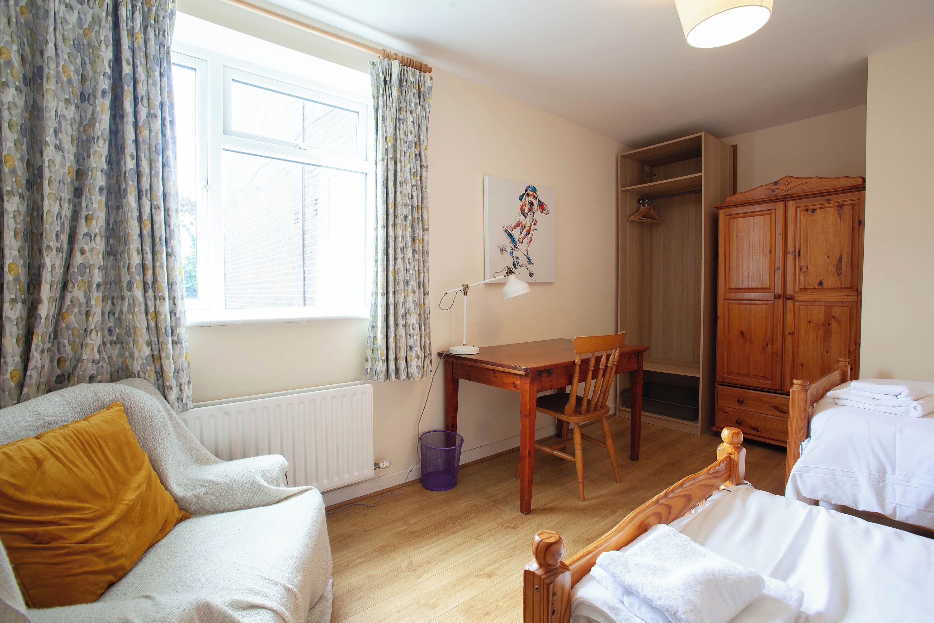 Une chambre à coucher avec un lit, une armoire en bois, un bureau avec une chaise et un radiateur.