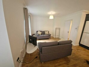 A living room with a grey sofa, a TV, and a small table. - Spacious Bright Modern Apt With Garden (Dublin)