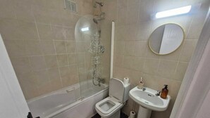 Une salle de bain équipée d’une baignoire, de toilettes, d’un lavabo et d’un espace douche.