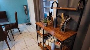 Una cocina con estante de madera que sostiene utensilios, una planta en maceta y una ventana con vistas.