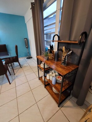 Een keuken met een houten plank waarop keukengerei, een plant in pot en een raam met uitzicht.