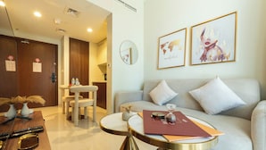 A modern hotel room with a sofa, a round table, a small decorative vase, and a world map artwork on the wall. - Keyrock Living | Stylish Lakeview in Business Bay (Dubai)