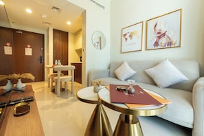 A modern hotel room with a sofa, a round table, a small decorative vase, and a world map artwork on the wall. - Keyrock Living | Stylish Lakeview in Business Bay (Dubai)