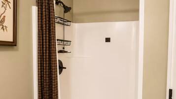 Une douche avec un rideau à carreaux, un porte-serviettes et un tableau encadré au mur.