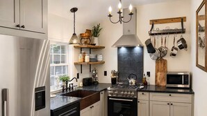 Una cocina moderna con electrodomésticos de acero inoxidable, una estufa a gas, un microondas y una variedad de utensilios colgados en la pared.