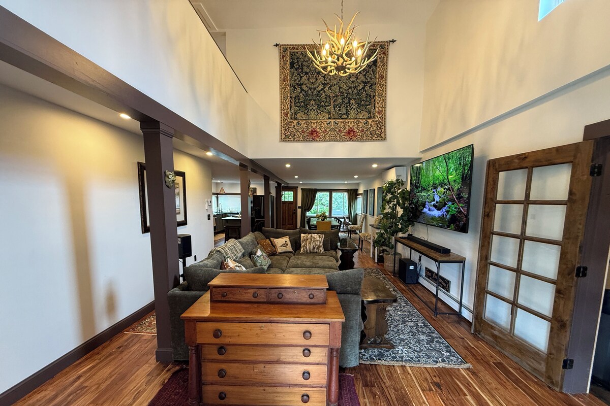 A spacious living room with a large sofa, a wooden coffee table, and a television on the wall.