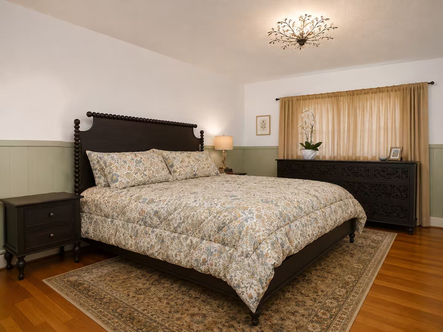 A neatly arranged bedroom with a bed, nightstand, dresser, and a chandelier.