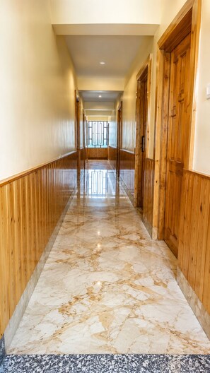 Un pasillo con paneles de madera y suelo de mármol que conduce a una puerta.