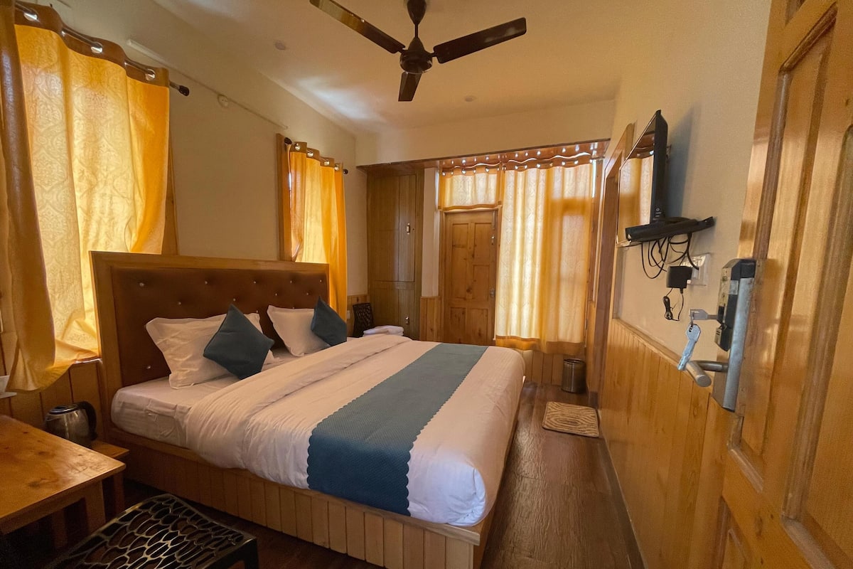A bedroom with a wooden bed, a ceiling fan, a wooden wardrobe, and a bedside table.