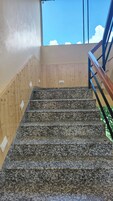 Una escalera con paredes de madera y barandilla de metal.