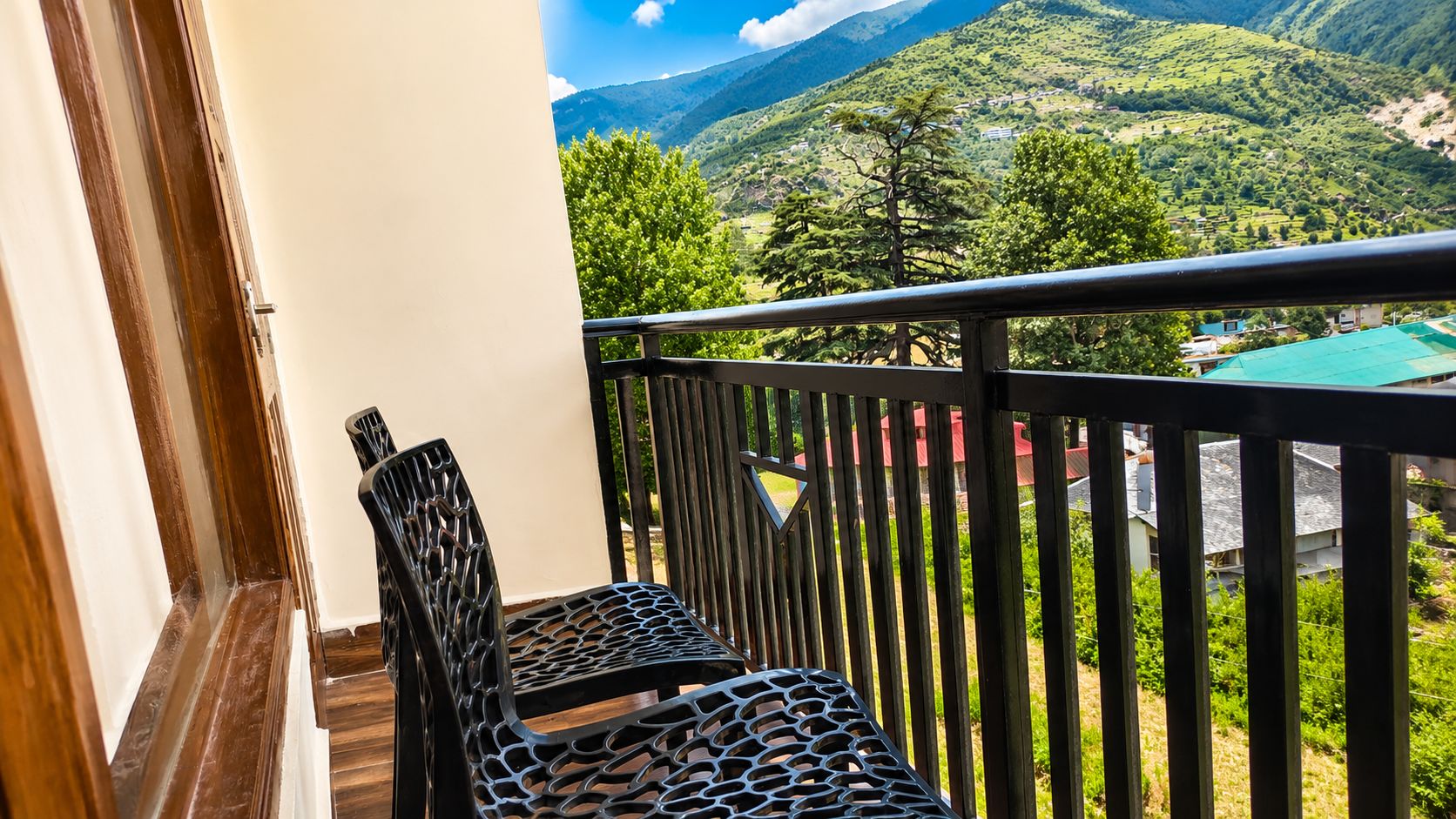 A balcony with two chairs and a view of a mountainous landscape.