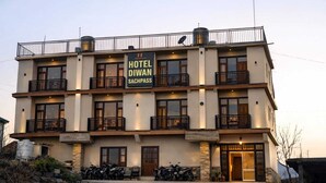 Een hotel met meerdere verdiepingen, balkons, een bord met de tekst 'HOTEL DIWAN SACHPASS' en enkele motorfietsen voor de gevel.