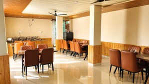 Een restaurant met houten lambrisering, een plafondventilator en een gepolijste vloer.