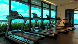 Eine Reihe von Laufbändern der Marke 'SPIRIT' in einem Fitnessstudio mit großen Fenstern und Blick auf eine Stadtlandschaft.