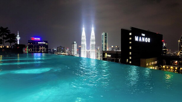 Ein Pool mit Stadtansicht im Hintergrund, darunter das Gebäude Marina 101 und die Petronas Towers.