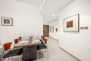 A modern dining area with a long table, chairs, and framed artwork on the walls. - FIRST CLASS | 1BR | Burj Khalifa & Fountain View (Downtown)
