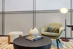 A modern room with a round coffee table, a green armchair, a floor lamp, and a vase on the table. - FIRST CLASS | 1BR | Burj Khalifa & Fountain View (Downtown)