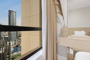 A hotel room with a view of a cityscape, a bed, a bedside table with a vase, and a window with curtains. - FIRST CLASS |2BR| Exquisite Escape Near JBR Beach (JBR)