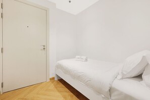 A minimalist room with a bed, a white door, and a wooden floor. - FIRST CLASS |2BR| Exquisite Escape Near JBR Beach (JBR)