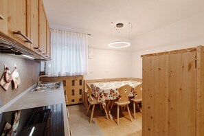 Keittiössä on puukehikoiset kaapit, sisäänrakennettu uuni, pesuallas sekä ruokapöytä tuoleineen.