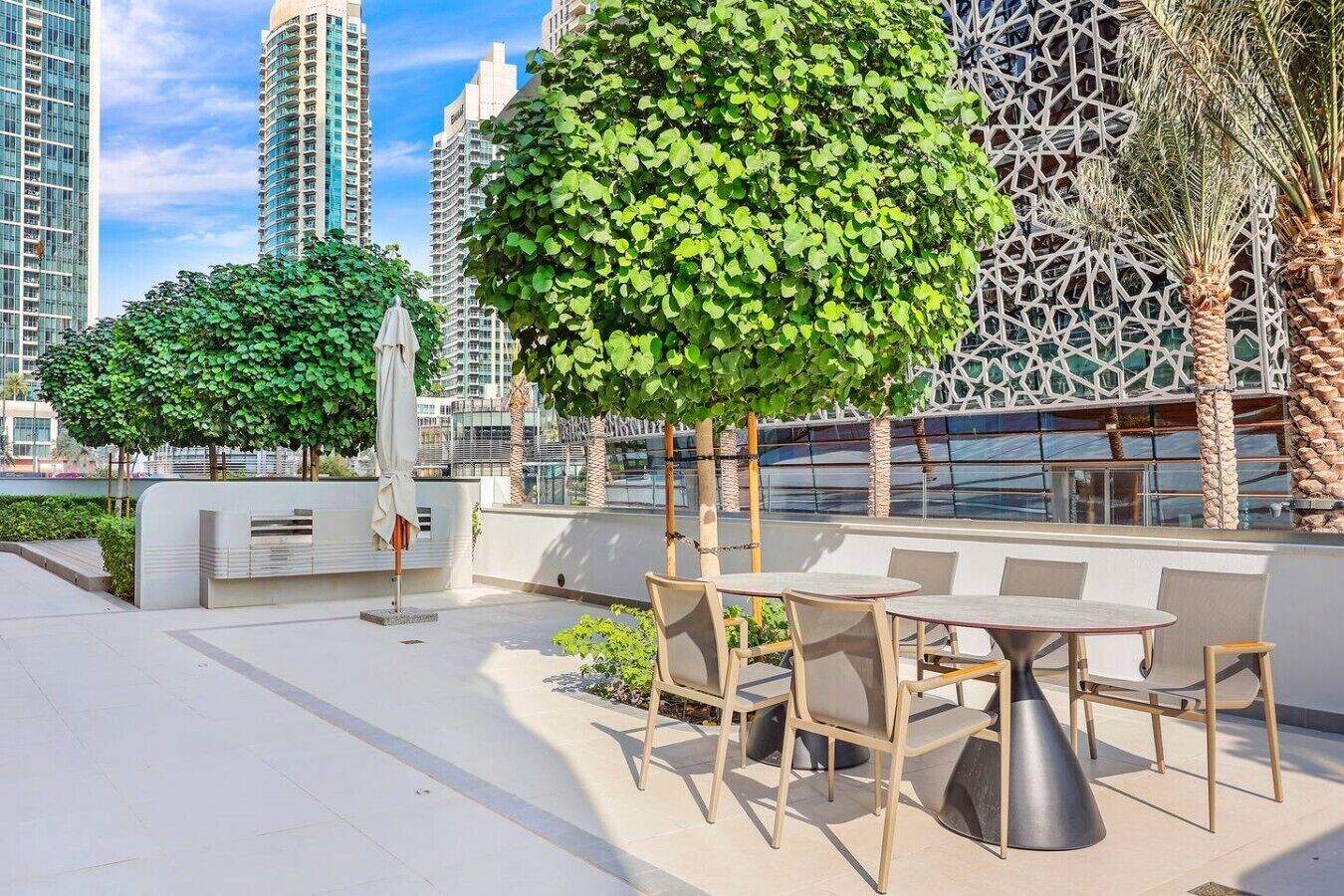 Une terrasse sur le toit avec des sièges extérieurs, un mur décoratif et de grands immeubles en arrière-plan.