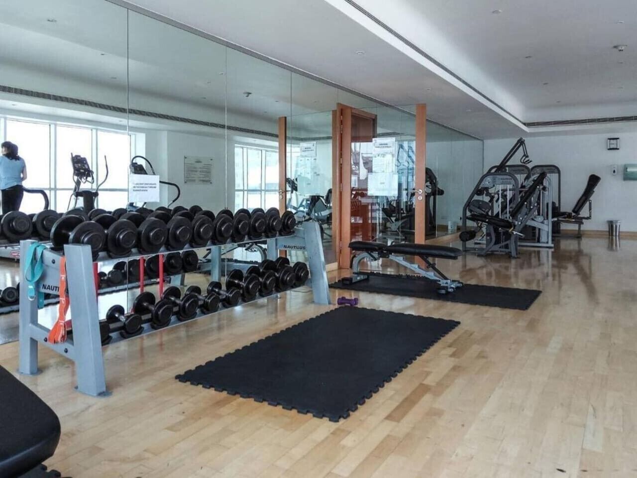 Ein Fitnessstudio mit Krafttrainingsgeräten, Laufbändern und einer Spiegelwand.