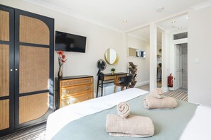 Une chambre d’hôtel équipée d’un lit, d’un bureau, d’une chaise, d’une télévision, d’un miroir et d’un extincteur.