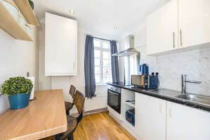 Une cuisine compacte comprenant une table à manger, des chaises, un four à micro-ondes, un grille-pain et un évier.